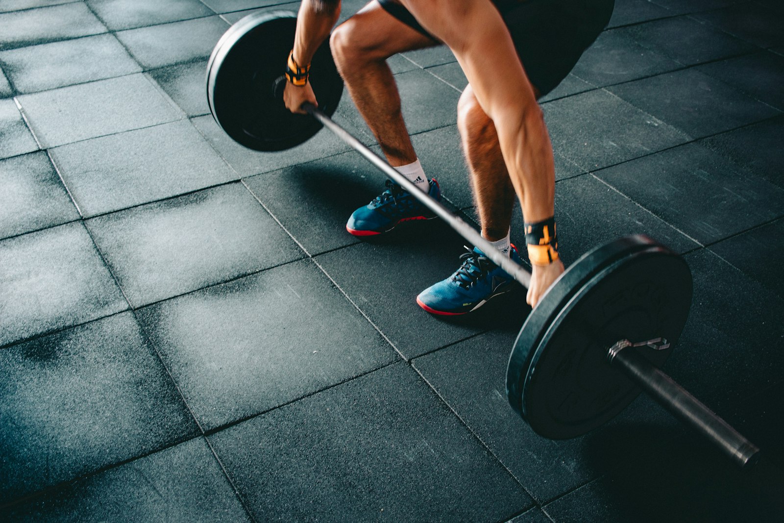 A lifter mid-pull over a loaded barbell on a rubber gym floor